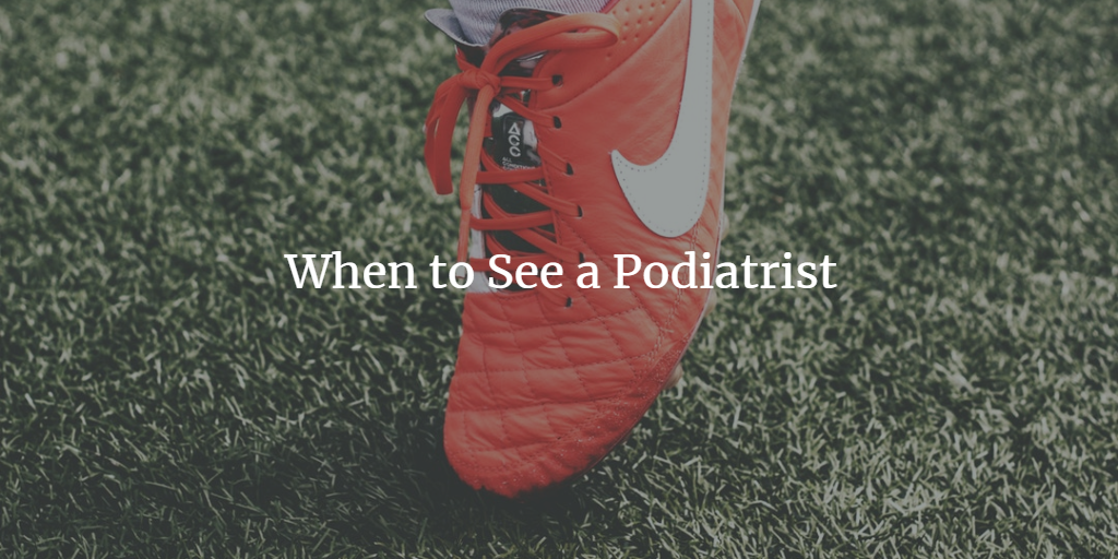 A close-up of a person’s foot wearing a bright red Nike soccer shoe on green artificial turf, with the text “When to See a Podiatrist” overlaid on the image.